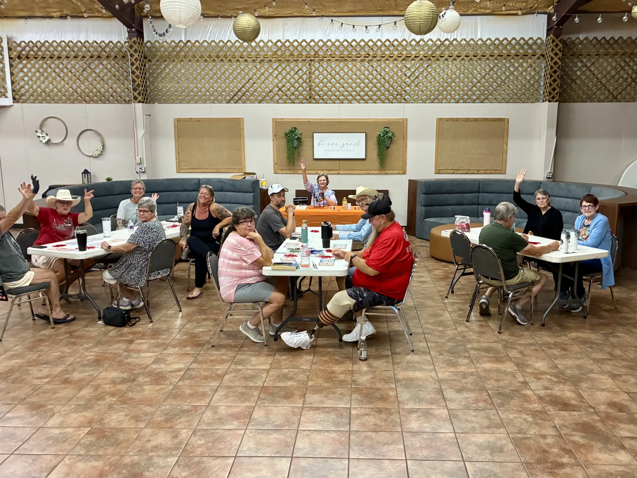 Park guests raising their hands during a bingo game at tables inside the Activity Center at Antique Capital RV Park