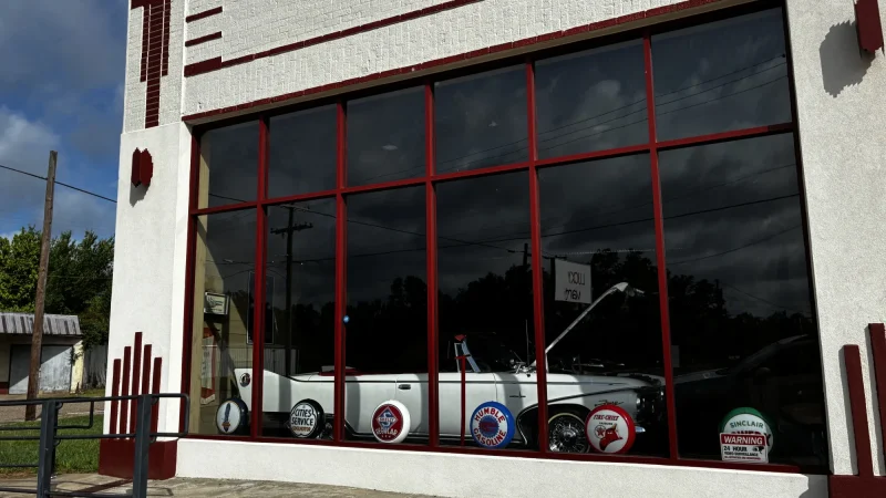 Vintage art deco storefront with a classic convertible car and antique gas station signs in downtown Gladewater, Texas